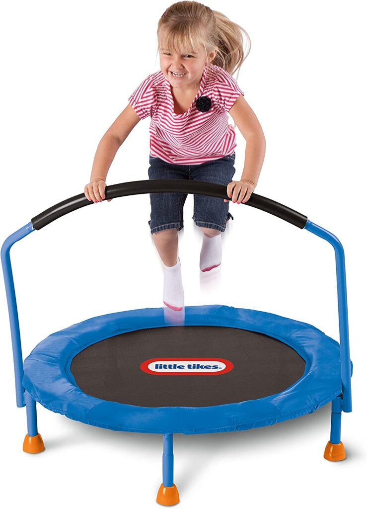 A little girl is seen holding jumping on a small trampoline while onto an attached handlebar.