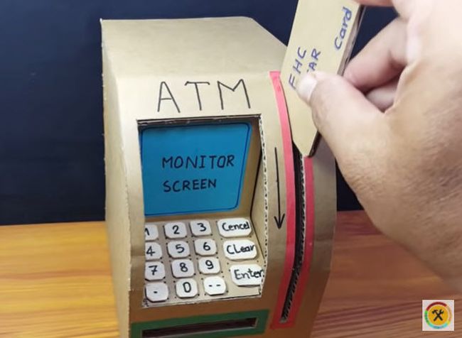 ATM made of cardboard with hand swiping a pretend ATM card