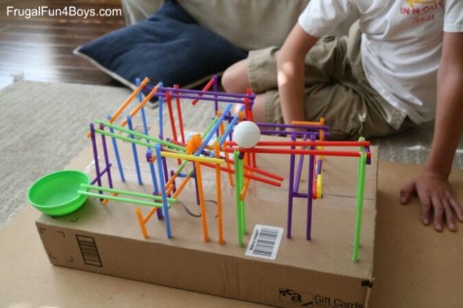 Child playing with a "roller coaster" built from drinking straws
