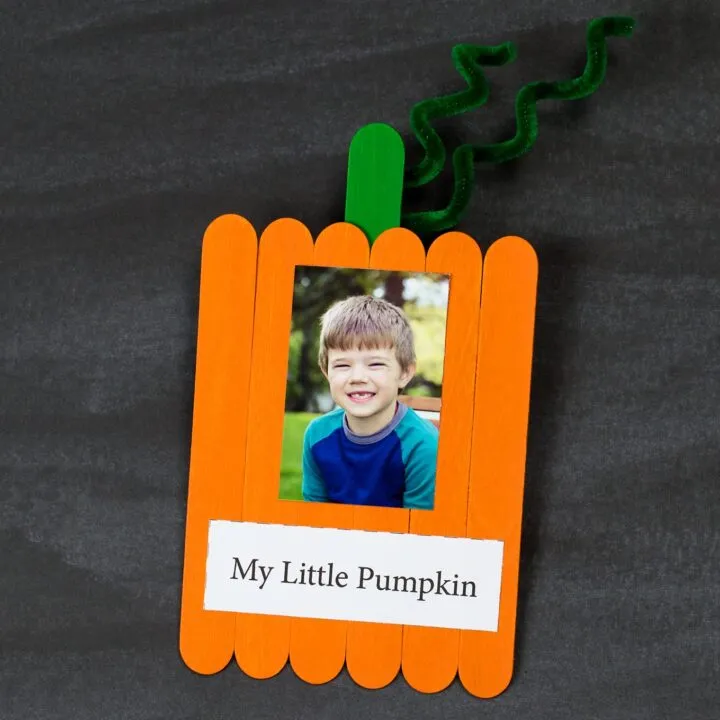Fall art projects like this one shows six orange popsicle sticks are glued together and a green one is in the back for a stem. A picture of a little boy is glued on it and the words "My Little Pumpkin." 