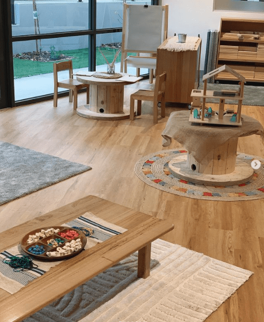 Natural tables and chairs and a neutral color palette in a kindergarten classroom