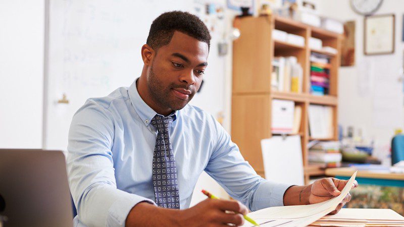 Teacher at a desk looking at a document