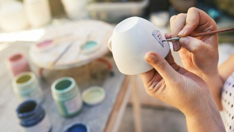 white woman's hands painting pottery