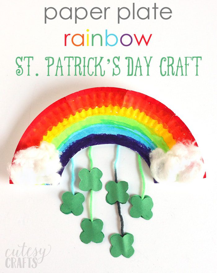 A paper plate is cut into a rainbow shape and painted rainbow colors. Shamrocks hang down from it like a mobile and white clouds are made of cotton at either end (St. Patrick's Day crafts for kids)