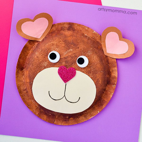 A Teddy bear face is made from a paper plate with googly eyes and the ears are made from hearts (Valentine's Day Crafts for Preschoolers)