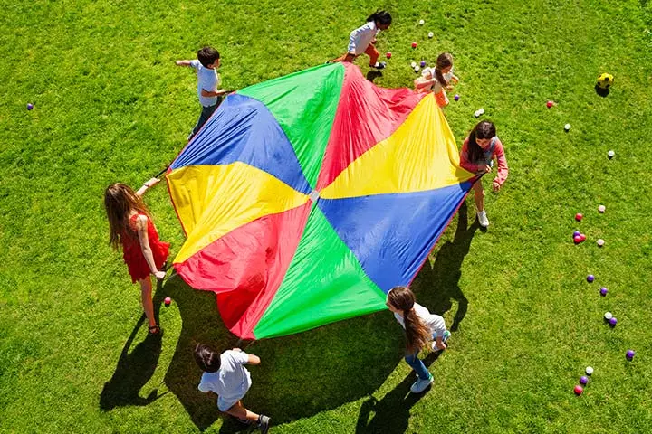 Students stand around a brightly colored parachute.