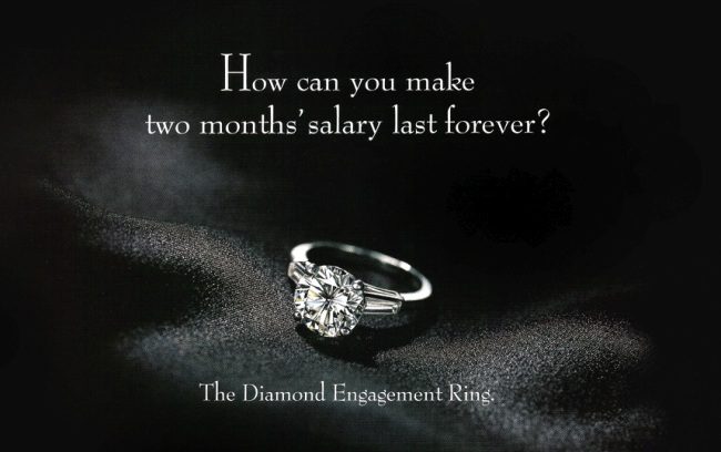 Diamond engagement ring on black velvet. Text reads "How do you make two months' salary last forever? The Diamond Engagement Ring."