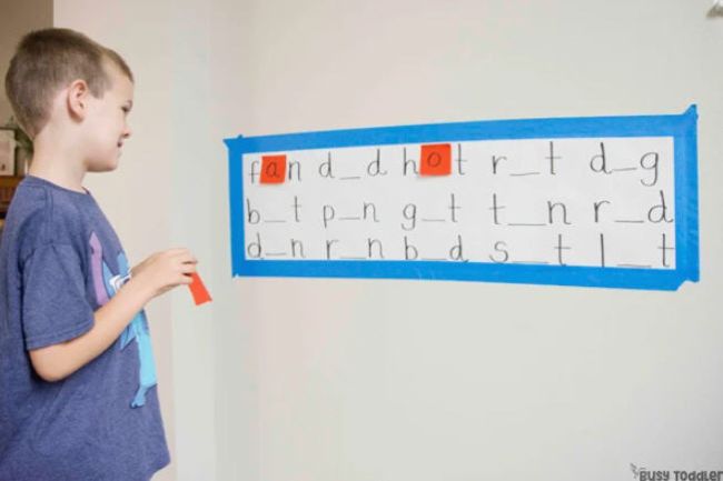 Elementary student using sticky notes to fill in the missing letters in CVC words (Phonics Activities)