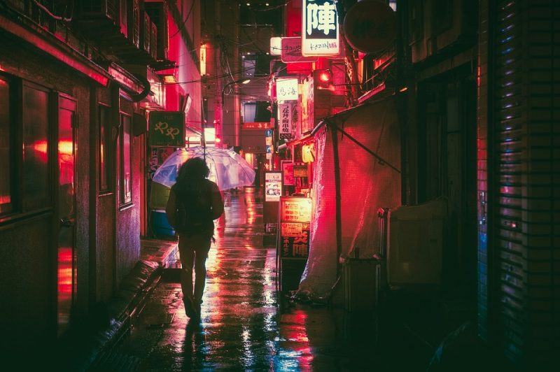 Un hombre que sostiene un paraguas camina por una calle llena de luces de neón.