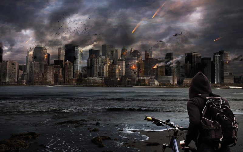 Un niño se para junto a su bicicleta y observa cómo llueven bombas sobre el horizonte de la ciudad (leyenda de la imagen).