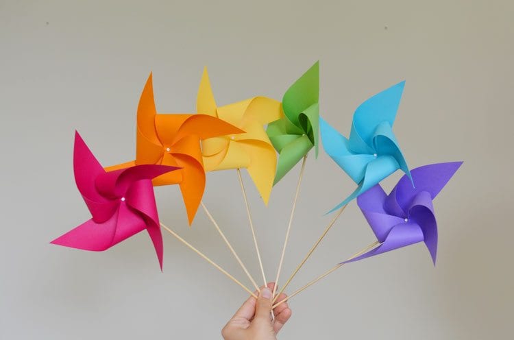 a hand holding up six colorful pinwheels