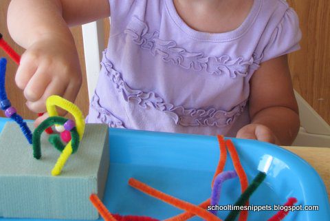 A little girl is shown sticking pipe cleaners into a foam block. (fine motor activities)