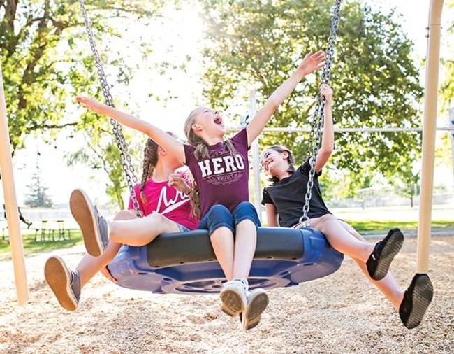 Children playing on a disc swing on a playground (Best Playground Equipment for Schools)