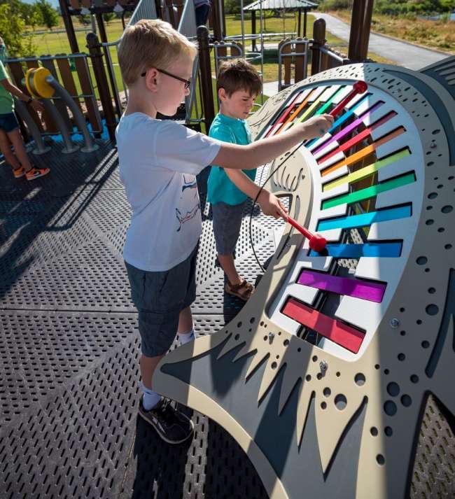 Children playing with an outdoor oversized xylophone