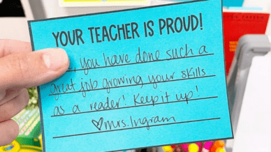 一只握着“你的老师感到骄傲的手！”在蓝色纸上注意