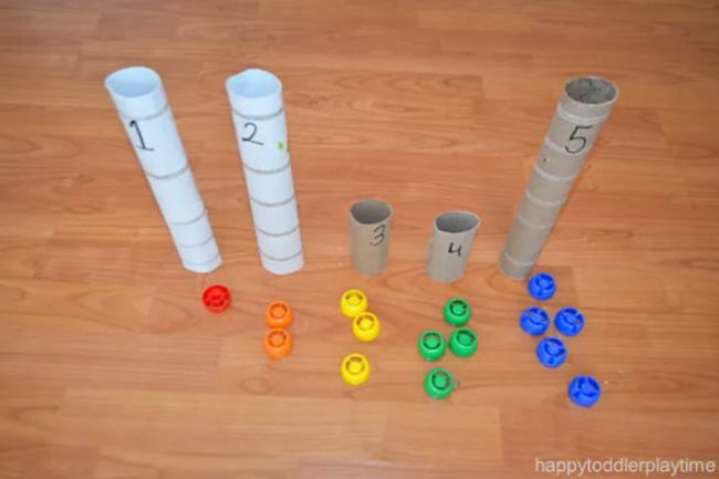 Plastic caps lined up next to cardboard tubes labeled with numbers (Preschool Math Games)