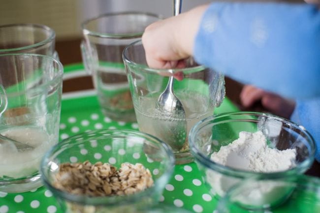 Preschool science student mixing various solids into glasses of water