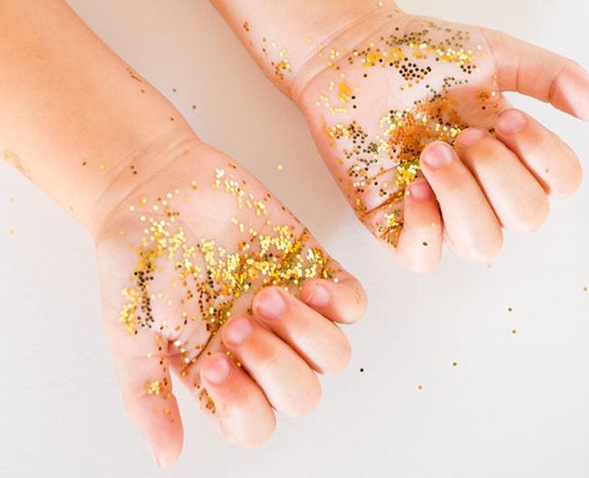 Young child's hands covered in gold glitter