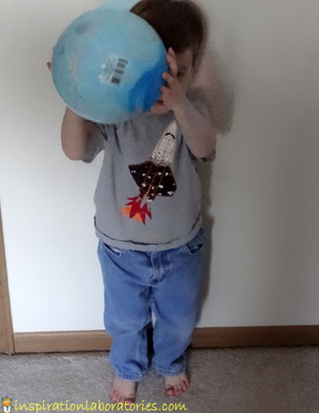 Toddler holding a blue rubber ball