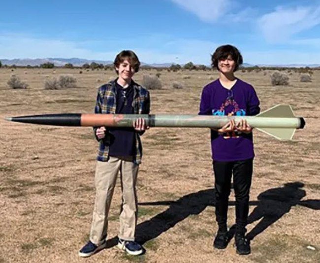 Two students holding a large model rocket built as part of project based learning