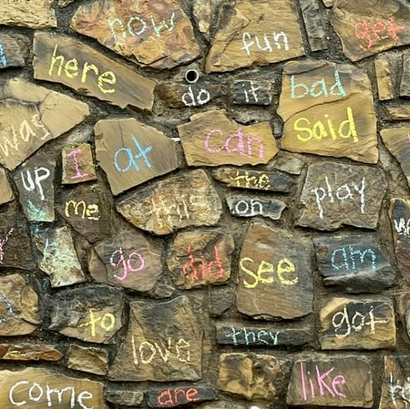 A variety of sight words written on small rocks in chalk