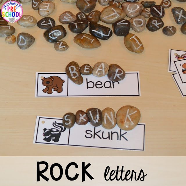 A desk is shown with river rocks with white letters painted on them. The words bear and skunk are written on strips of papers with matching river rock letters above them. 