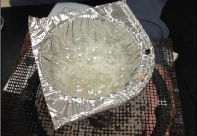 Aluminum foil bowl filled with bubbling liquid over a bunsen burner