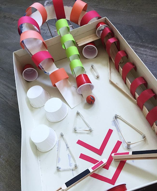 Student-created pinball machine made from cardboard box, paper cups, and other basic supplies