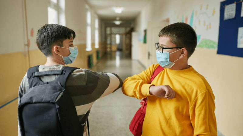 two elementary school boys tapping elbows in the hallway at school to build resilience in students