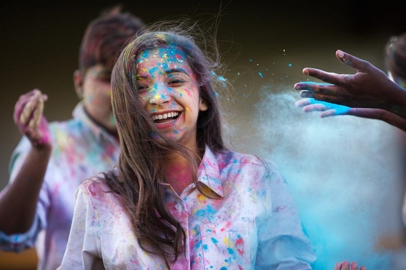 young, smiling girl with colored paint on her face and shirt - motivating students