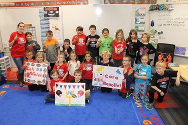 Classroom smiling while holding up signs they made