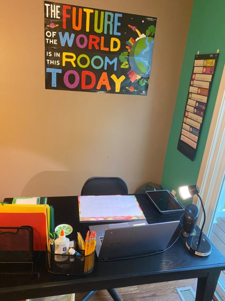 Teachers desk in space-themed classroom with space poster on wall that says, "The Future of the World in in This Room Today"