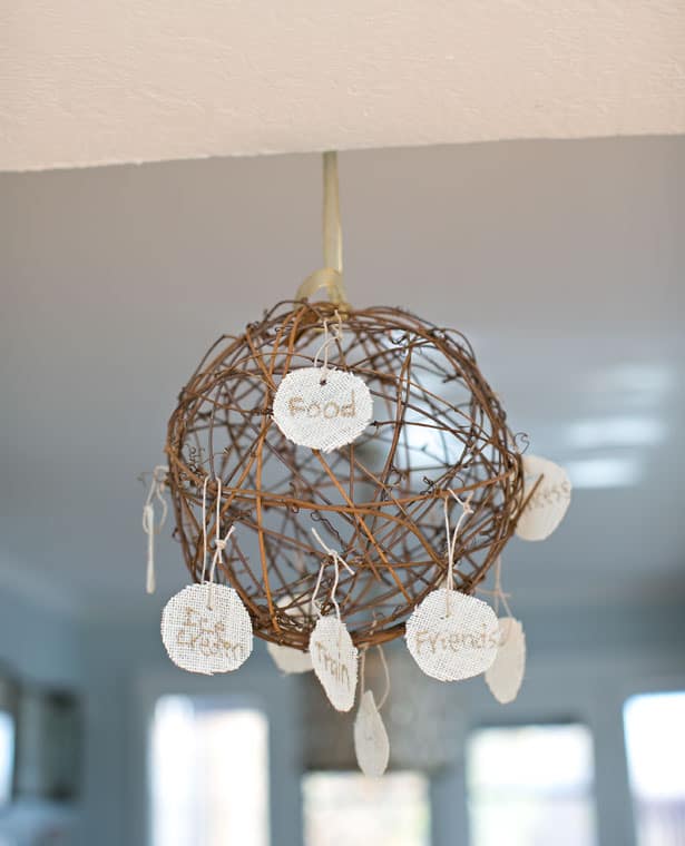 A twine ball has burlap ornaments hanging from it with things written on them that students are thankful for.