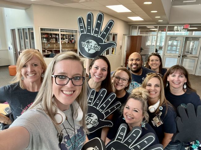 School staff wearing large foam hands with the school logo on them (School Spirit Week Ideas)