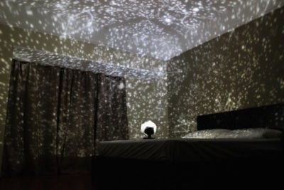 DIY classroom space themed wall projector casting stars in dark room