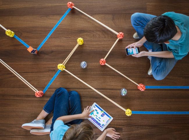 Two students playing with a tablet and a simple maze (STEM Activities)