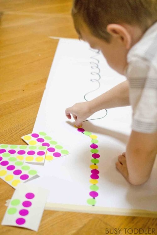 Child placing colorful stickers along a printed line