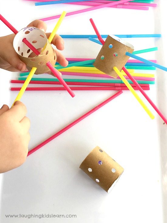 small cardboard rolls have holes punched in them.  Little hands are shown threading plastic straws through them (fine motor activities)