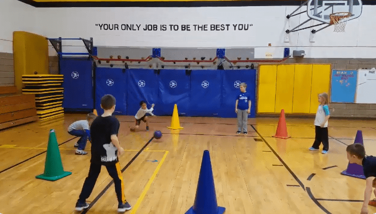 Large cones and students are spread around a gymnasium.