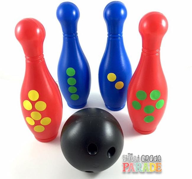 Four plastic bowling pins with arrangements of dot stickers, and a black plastic bowling ball