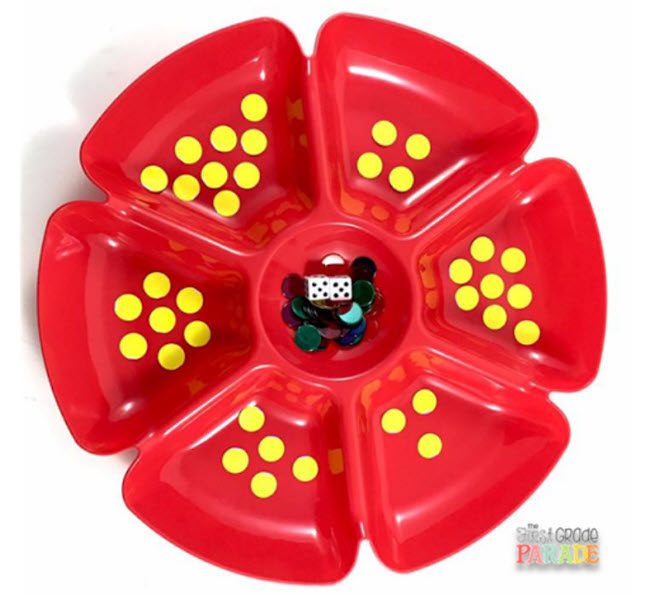 Divided red plastic chip and dip tray with yellow dots in each section, and plastic chips and a die in the mdidle