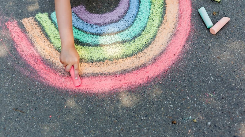Student draws a rainbow with colored chalk on the asphalt. Child drawings paintings concept. Education and arts, be creative when back to school