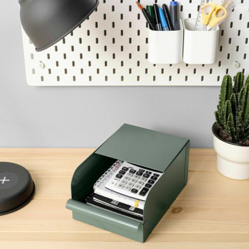 A green metal box is shown on a desk with a calculator and notebooks inside.