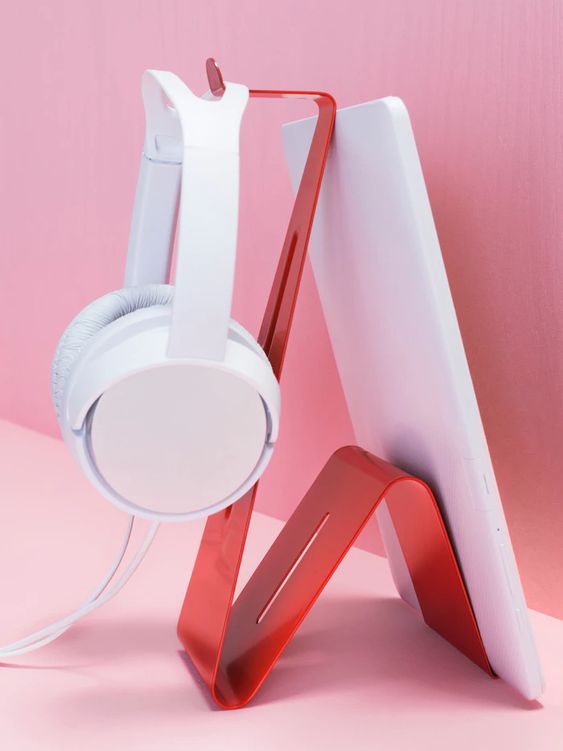 A red z shaped stand is shown holding both a tablet and a set of headphones, as an example of IKEA classroom supplies.