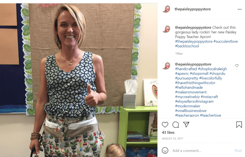 Teacher posing for a photo in her classroom while wearing a teacher apron with cute animals on it