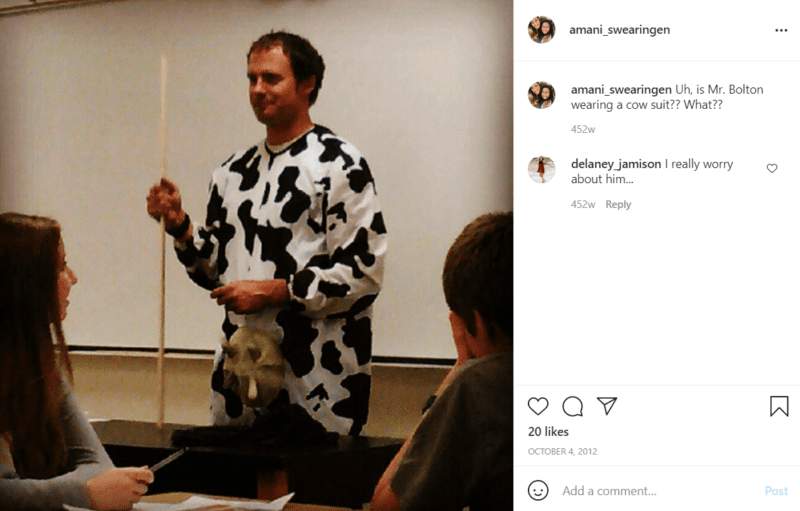 Teacher standing in front of a whiteboard in a classroom dressed in a cow costume
