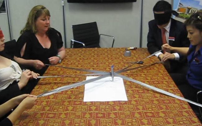 Teachers using strings to pull a single pen and write a word (Team Building Games for Adults)