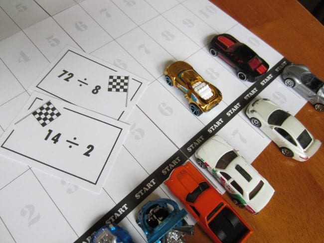 Toy cars lined up with division flash cards