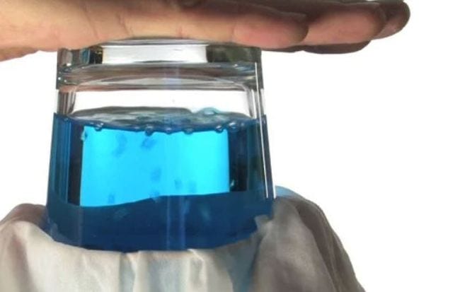 Ein Wasserglas wird auf den Kopf gestellt, und im Inneren entstehen Blasen