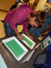 Student trying to pick up a tic-tac with a pair of tweezers, as an example of pep rally activities and games